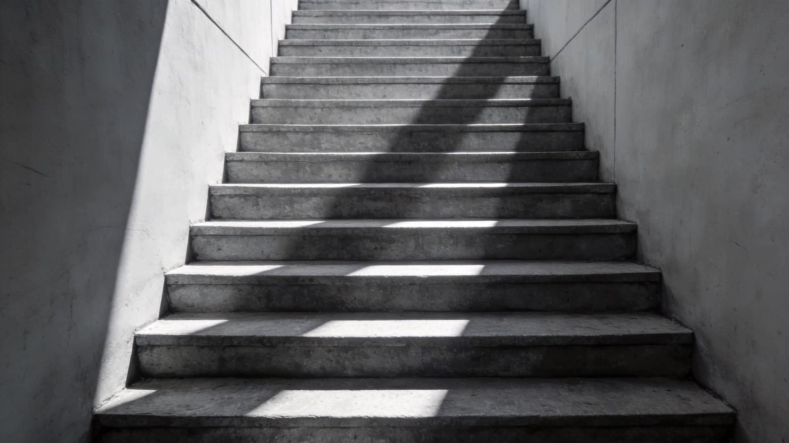 A flight of broad stone steps rising between plain walls, raking light across each tread
