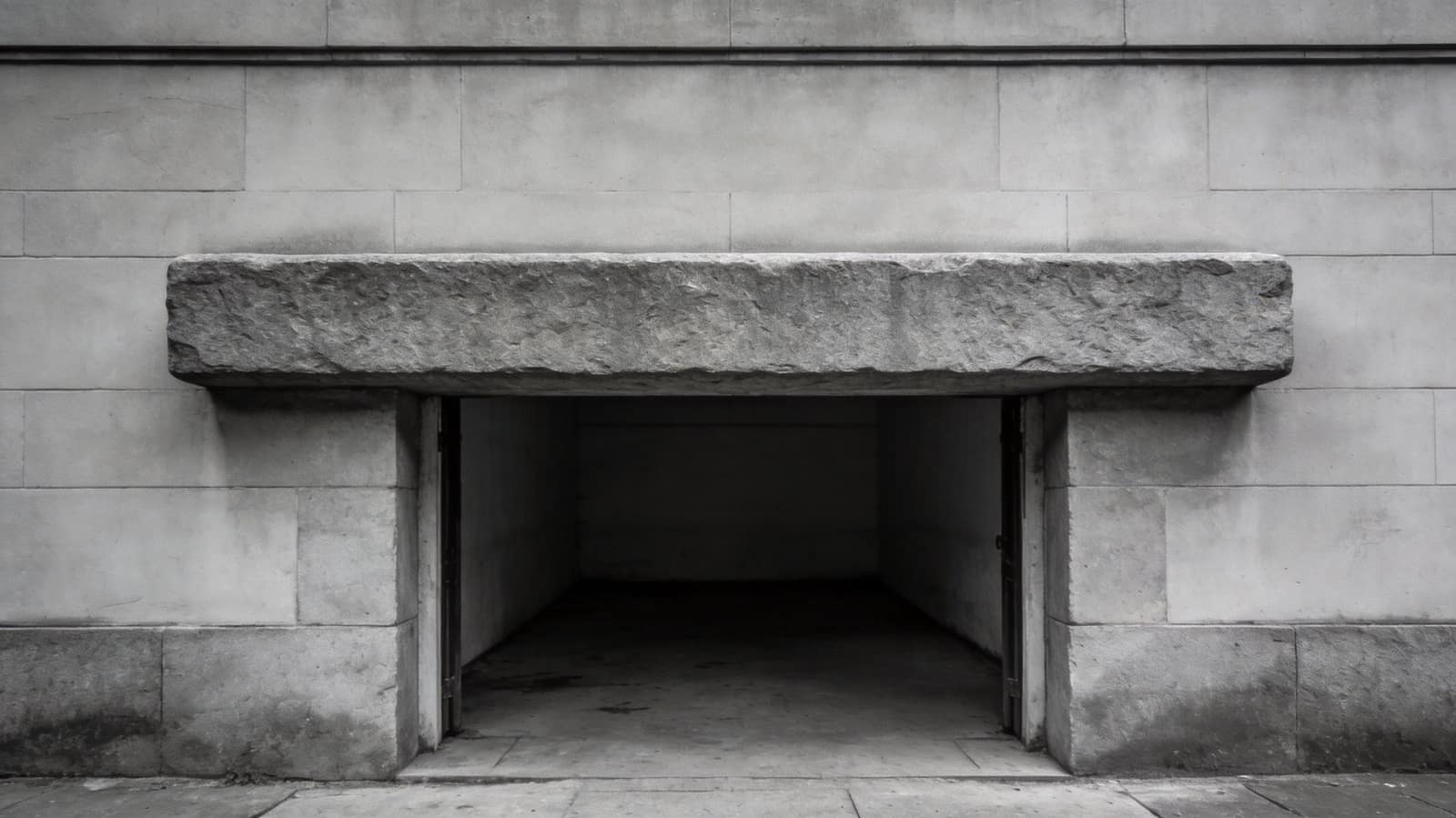 A plain stone lintel spanning a doorway, one long unbroken block, photographed square on