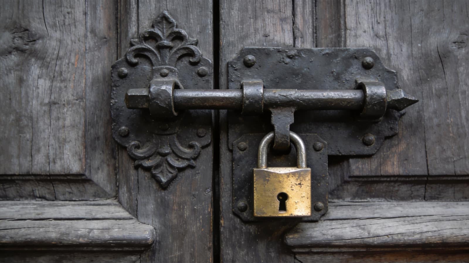 A wrought-iron bolt thrown home across a heavy oak door, its keeper plate worn bright by use