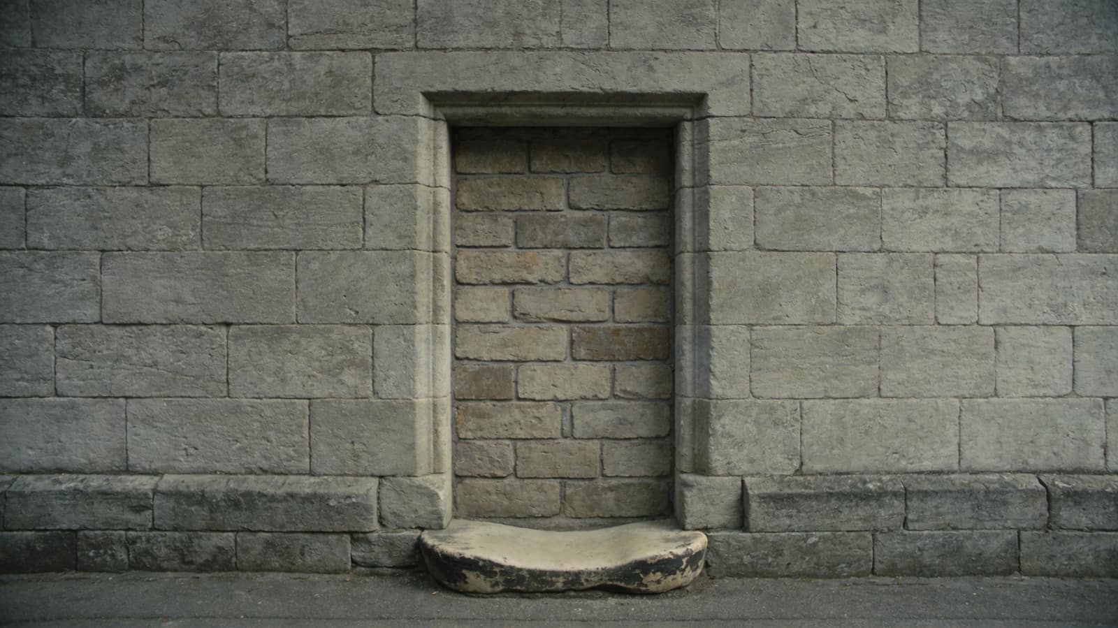 A stone doorway bricked up flush with mismatched newer stone, its threshold step worn hollow by traffic that no longer passes